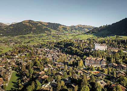 Luftaufnahme vom Dorf Gstaad im Sommer mit wolkenlosem Himmel.