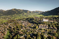 Luftaufnahme vom Dorf Gstaad im Sommer mit wolkenlosem Himmel.