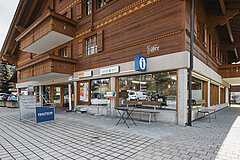 Traditional wooden chalet in Saanenmöser housing a village shop, café, post office, and tourist information point on the ground floor.