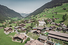 Ein Dorf mit vielen Holz Chalets inmitten von grünen Wiesen und Wäldern.