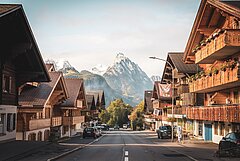 Eine malerische Dorfstraße mit traditionellen Chalets und Blick auf majestätische Berge im Hintergrund. Die Umgebung ist ruhig und idyllisch, ideal für einen entspannenden Aufenthalt.