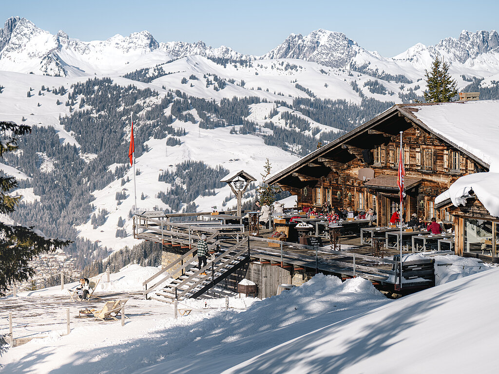 Bergrestaurant mit Terrasse und viel Schnee vor schöner verschneiter Bergkulisse.