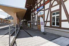 Zweisimmen railway station with tracks, modern platform and tourist information office inside a historic timber-framed MOB building.