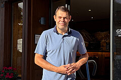 Staff member standing in front of the Gstaad Tourist Office entrance and looking outside.