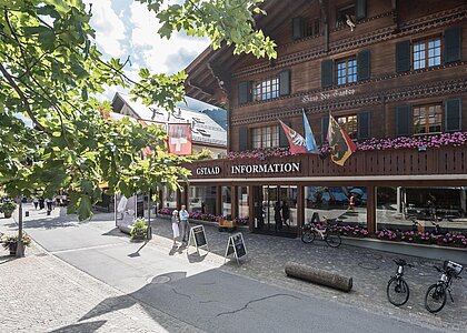 Ein typisches Schweizer Chalet mit touristischen Informationen. Draußen stehen Fahrräder und es blühen Blumen in den Fenstern.
