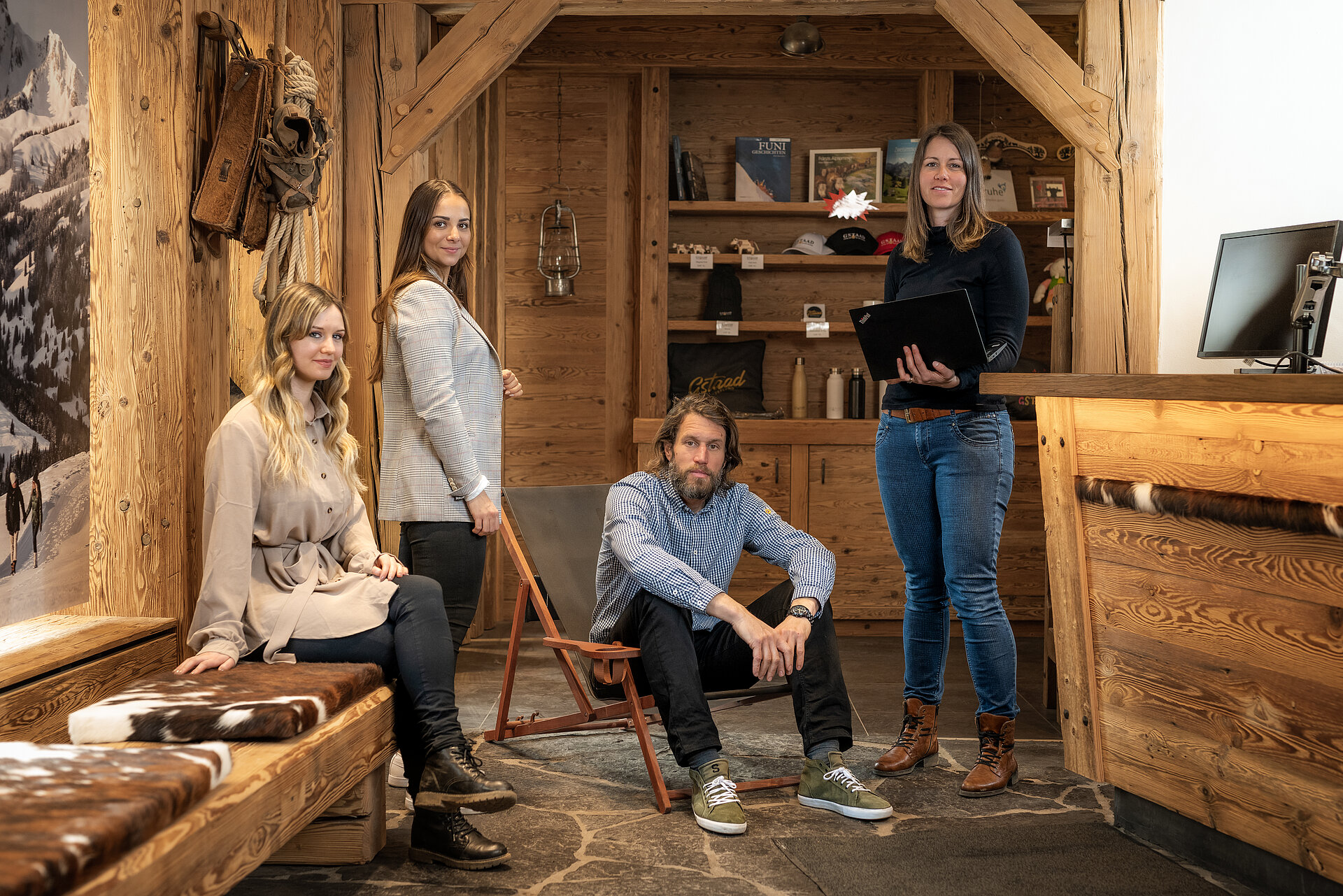 In einem urchigen Empfangsbüro erwarten drei Frauen und ein Mann gespannt ihre Gäste.