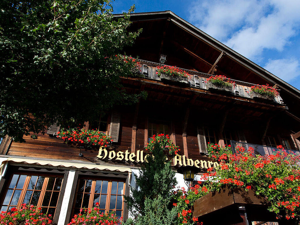 Aussenansicht des Hotel Alpenrose. Chalet-Haus mit roten Geranien.