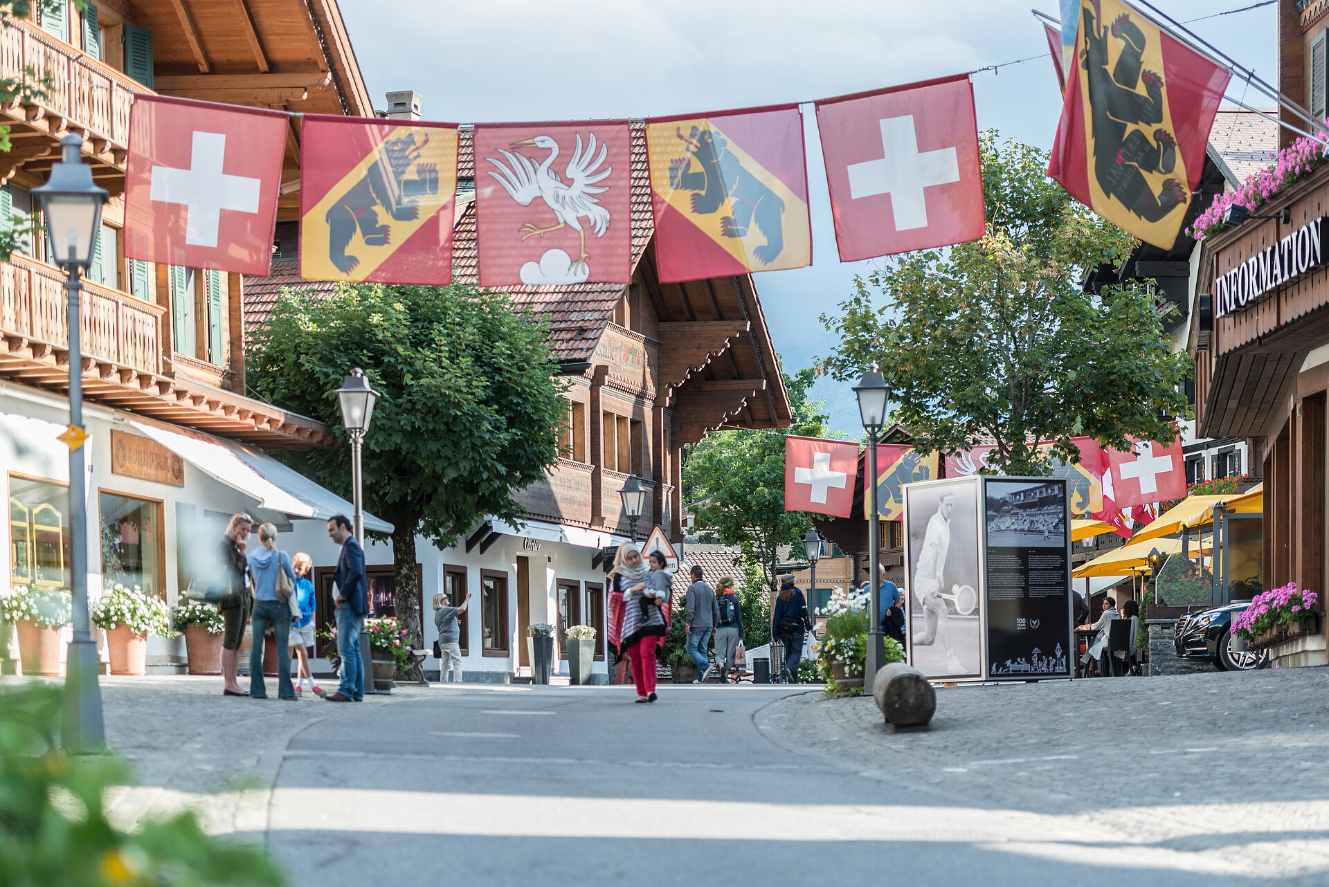 Fahnen der Schweiz, Bern und Saanen hängen über der Promenade in Gstaad.