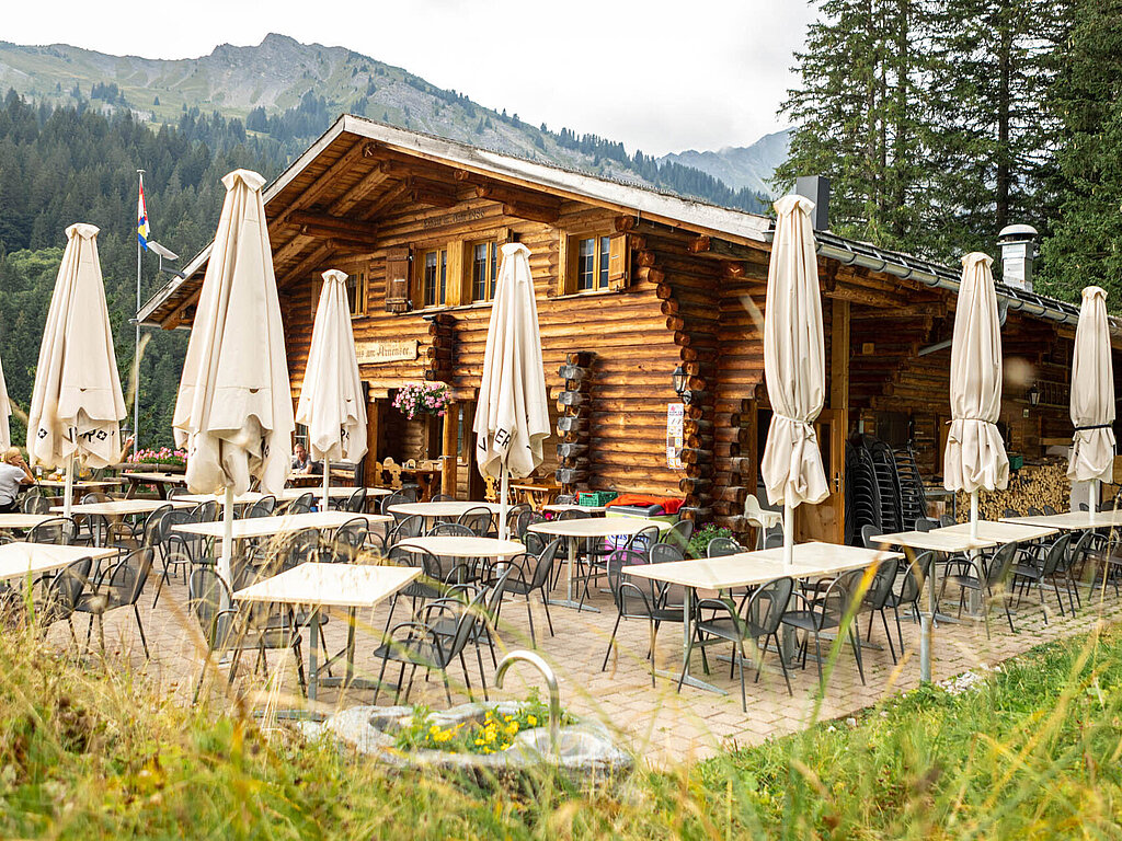 Ein Holzgebäude mit Tischen und Sonnenschirmen.