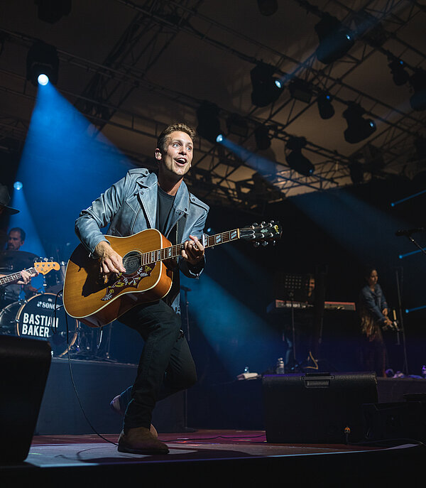 Sebastian Baker singing and playing with the band on stage at Country Night Gstaad.